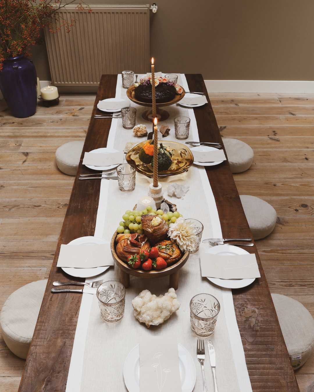 A long table set with candles, pastries and fruit
